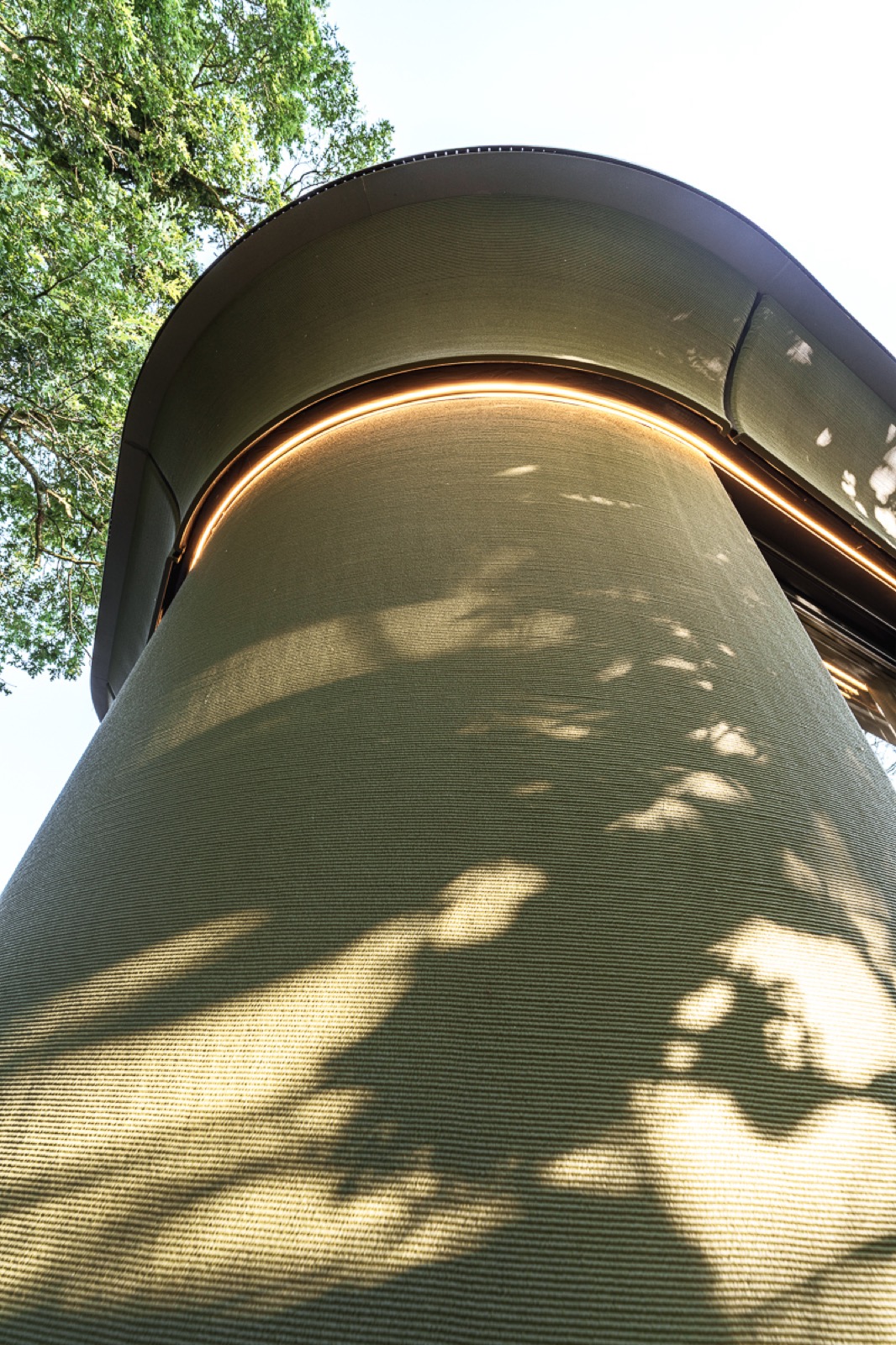 Close-up van de afgeronde Silva Embrace-gevel met warme lichtlijn onder de dakrand